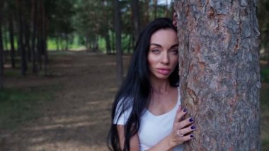 Ormanda bir ağacın yanında duran kadın.