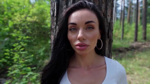 Жінка стоїть біля дерева в лісі — стокове відео