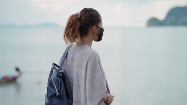 Young woman wearing protective face mask at viewpoint near the sea — Stock Video