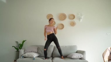 Kanepede zıplayan mutlu bir kadın eğlenceli bir dans ediyor. kutlama başarısı