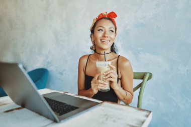 Kafede dizüstü bilgisayar kullanan genç bir Asyalı kadın.