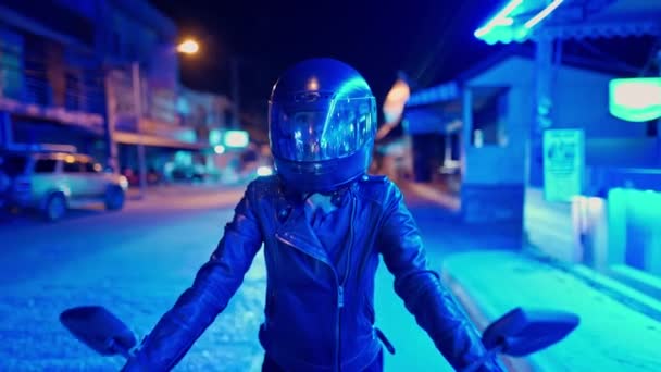 Жінка сидить на чорному мотоциклі в блакитному неоновому світлі. 4-кілометровий — стокове відео