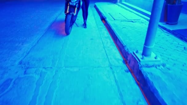 Femme assise sur une moto noire en néon bleu. 4K — Video