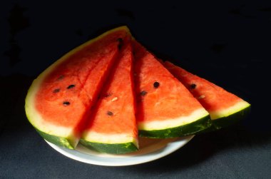 Siyah arka planda olgun karpuz. Dilimler meyvesi kırmızı posalı. Beslenmenin tatlı ürünleri
