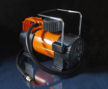 Cam masada yansımalı kompresör, siyah arka planda turuncu gövdeli ekipman.