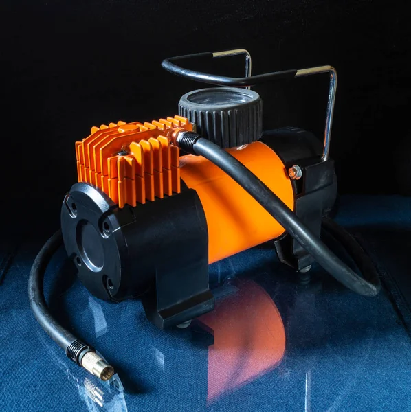 Autokompressor Auf Glastisch Mit Reflexion Ausstattung Mit Orangefarbenem Gehäuse Auf lizenzfreie Stockfotos