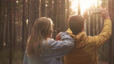 Genç adam ve kadın fotoğraf telefon ormandaki yaptırın