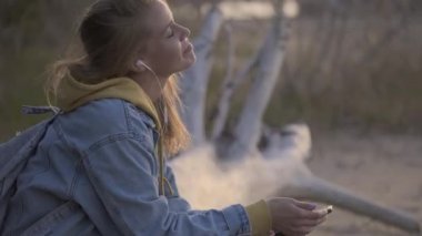 Seyahat kız sahilde oturup müzik dinlemek