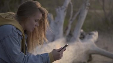 Sunset beach ve sohbet için akıllı telefon kullanan kız