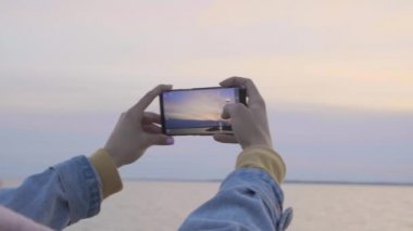 Telefon ile eller günbatımı sahil fotoğraf yapmak