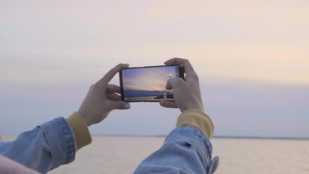 Ženské ruce s telefonem, aby Foto západu slunce u moře