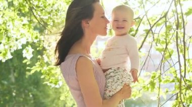 Anne, yeşil arka bahçesinde ağır çekim ile gülümseyen çocuk gülmek