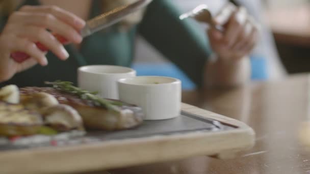 Table de restaurant et les mains de la femme mangeant steak — Video