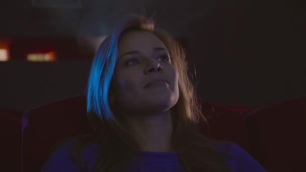 Жінка усміхнене обличчя дивиться фільм сидить у кіно — стокове відео