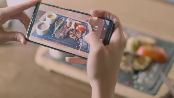 Las manos sostienen el teléfono y hacen una foto de comida en la cafetería — Vídeos de Stock