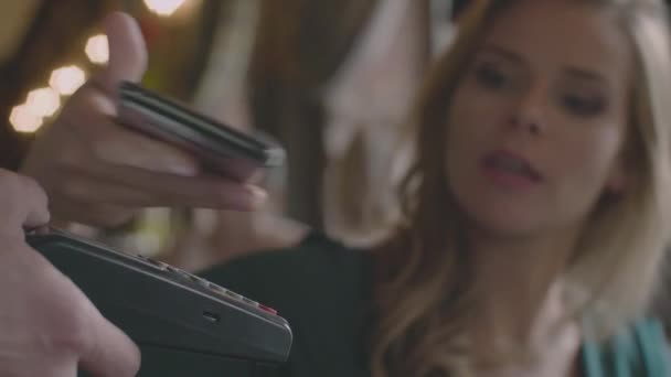 Женщина, использующая телефон для бесконтактной оплаты в кафе — стоковое видео