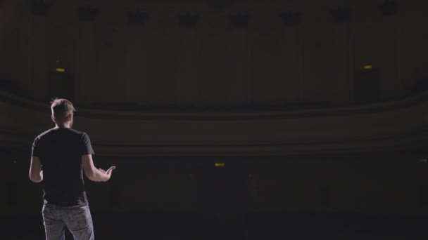 Discours d'homme debout sur la scène dans une grande salle sombre — Video