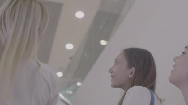 Chicas sonriendo en la escalera mecánica en el centro comercial — Vídeos de Stock