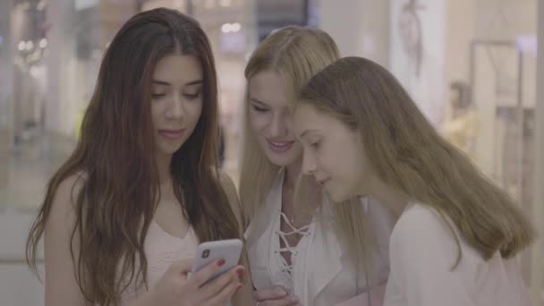 Meisjes vrienden kijken naar telefoon in winkelcentrum — Stockvideo