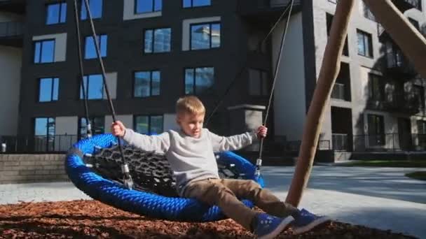 Barn pojke svängande i urbana lekplats slow motion — Stockvideo