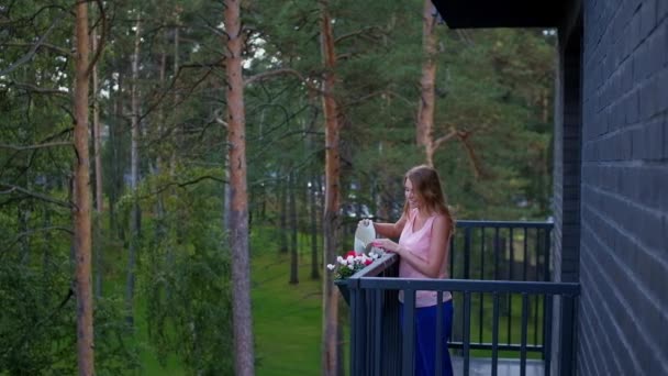 Γυναίκα πότισμα λουλούδια στο μπαλκόνι ύπαιθρο σπίτι — Αρχείο Βίντεο