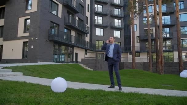 Hombre de negocios hablar en el teléfono inteligente al aire libre cerca de casa — Vídeo de stock