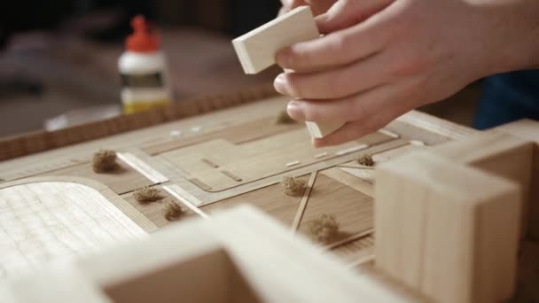 Handwerker arrangiert Gebäude auf einem hölzernen architektonischen Grundriss — Stockvideo