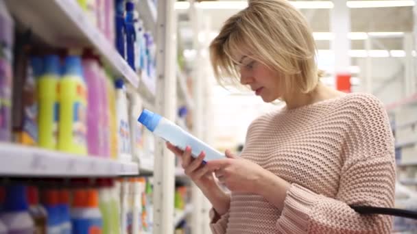 Mujer joven eligiendo productos más limpios en los estantes del supermercado y etiquetas de lectura — Vídeo de stock