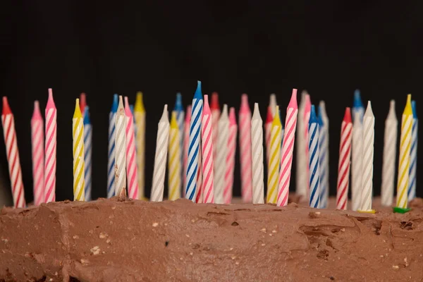 Čokoládový narozeninový dort se svíčkami na tmavém pozadí — Stock fotografie