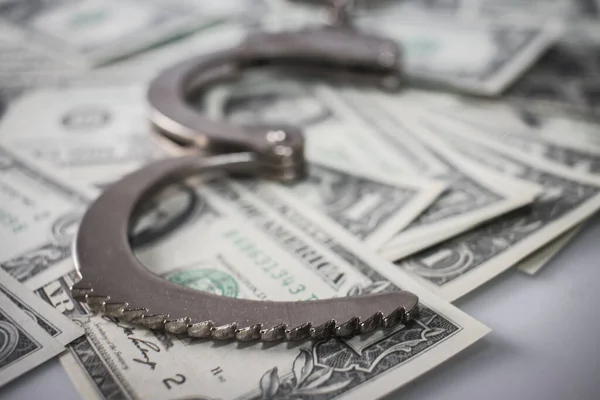 Handcuffs sitting on top of US paper currency — Stock Photo, Image