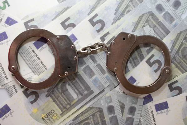 Handcuffs sitting on top of US paper currency — Stock Photo, Image