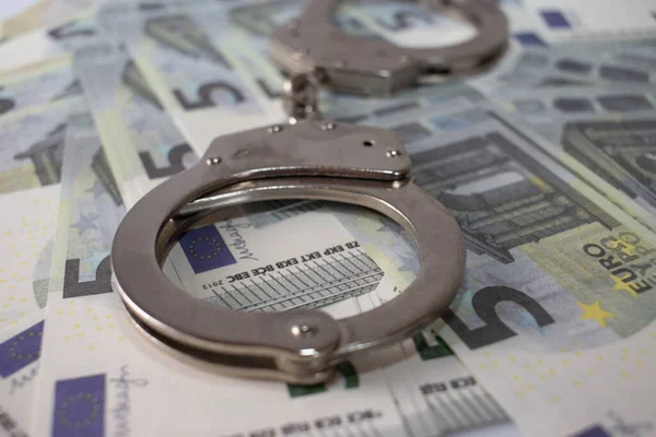 Handcuffs sitting on top of US paper currency — Stock Photo, Image