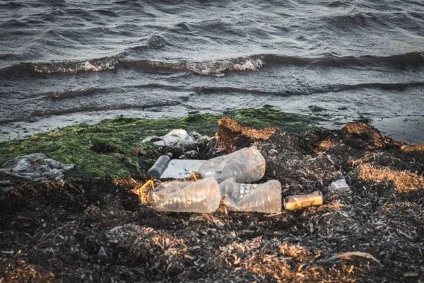 Plastic bottles left on the dirty sand beach with various garbages — Stock Photo, Image