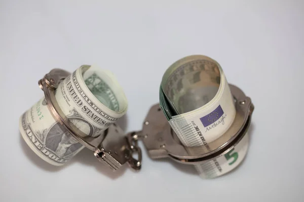 Счета по доллару и евро с наручниками на белом — стоковое фото