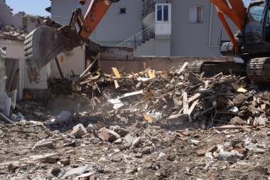 Kazıcı yıkılmış bir binanın enkazını yüklüyor