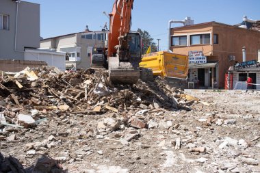 Urla, Türkiye - 13 Mayıs 2020: Kazıcı yıkılan bir binanın enkazını kamyonla yüklüyor.