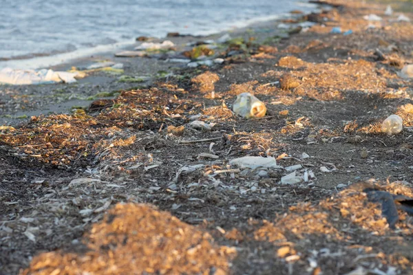 Plastic bottles left on the dirty sand beach with various garbages — Stock Photo, Image