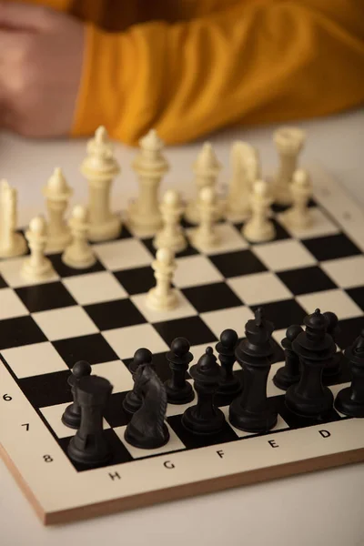 Siede a un tavolo e gioca a scacchi. Il ragazzo si è concentrato sul gioco — Foto Stock