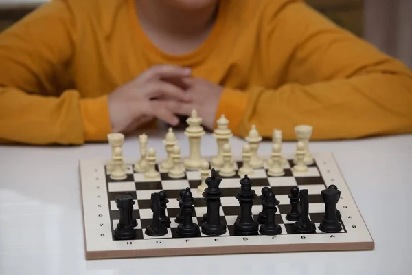 Sedí u stolu a hraje šachy. Ten kluk se soustředil na hru. — Stock fotografie