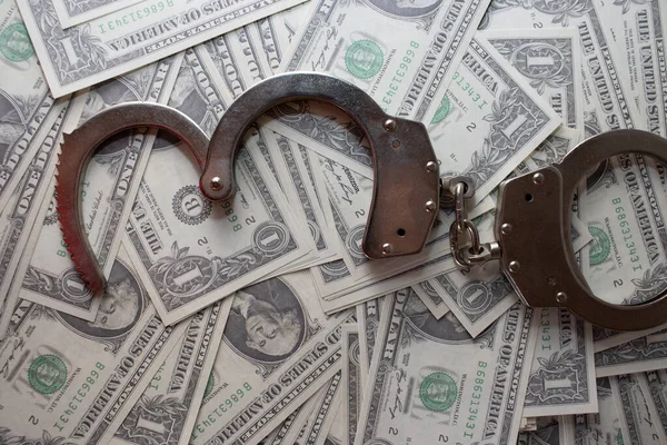 Handcuffs sitting on top of US paper currency — Stock Photo, Image