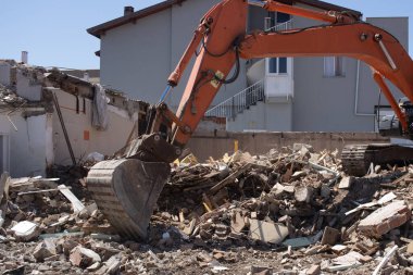 Kazıcı yıkılmış bir binanın enkazını yüklüyor