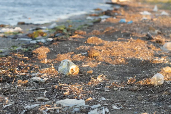 Plastic bottles left on the dirty sand beach with various garbages — Stock Photo, Image