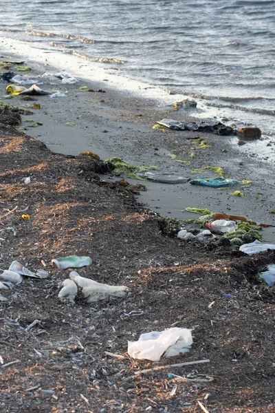 Plastic bottles left on the dirty sand beach with various garbages — Stock Photo, Image