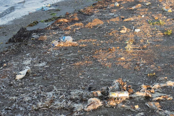 Plastic bottles left on the dirty sand beach with various garbages — Stock Photo, Image