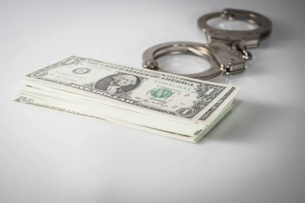 Handcuffs sitting on top of US paper currency — Stock Photo, Image