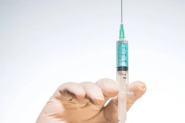 Hand wearing latex glove holding syringe with a medicine on white background — Stock Photo, Image