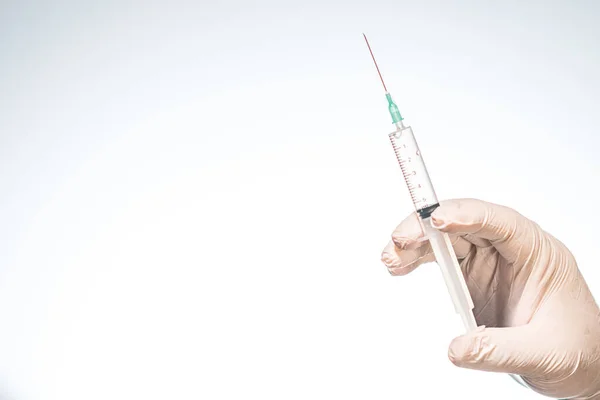 Hand wearing latex glove holding syringe with a medicine on white background — Stock Photo, Image