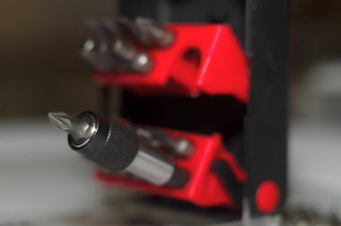 Kutuda parça tutucu ve beyaz arkaplanda bir sürü araç biti. Yakın çekim görüntüsü. Plastik kutuda kırmızı element.