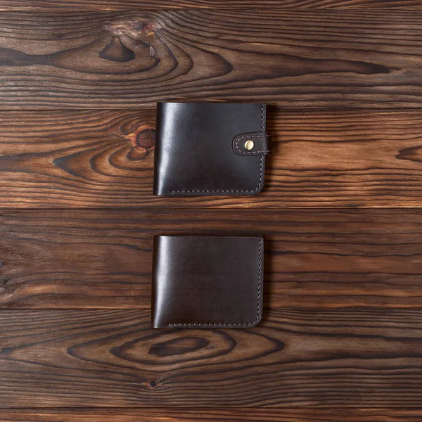 Brown handmade leather gloss wallets on wooden textured background. Up to down view. Businessman wallet stock photo.