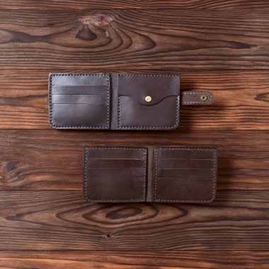 Ahşap desenli arka planda iki kahverengi el yapımı deri cüzdan. Görüş açımız düşük. Cüzdan stoğu fotoğrafı.